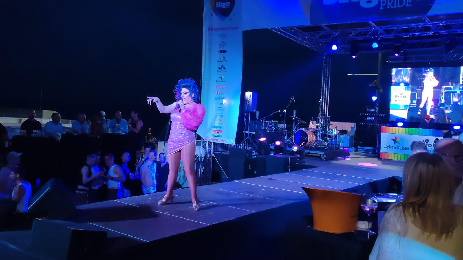 Público disfrutando de la actuación de Miss Mars, drag queen cantante y performer. Asistentes aplaudiendo y participando en el show de Miss Mars.